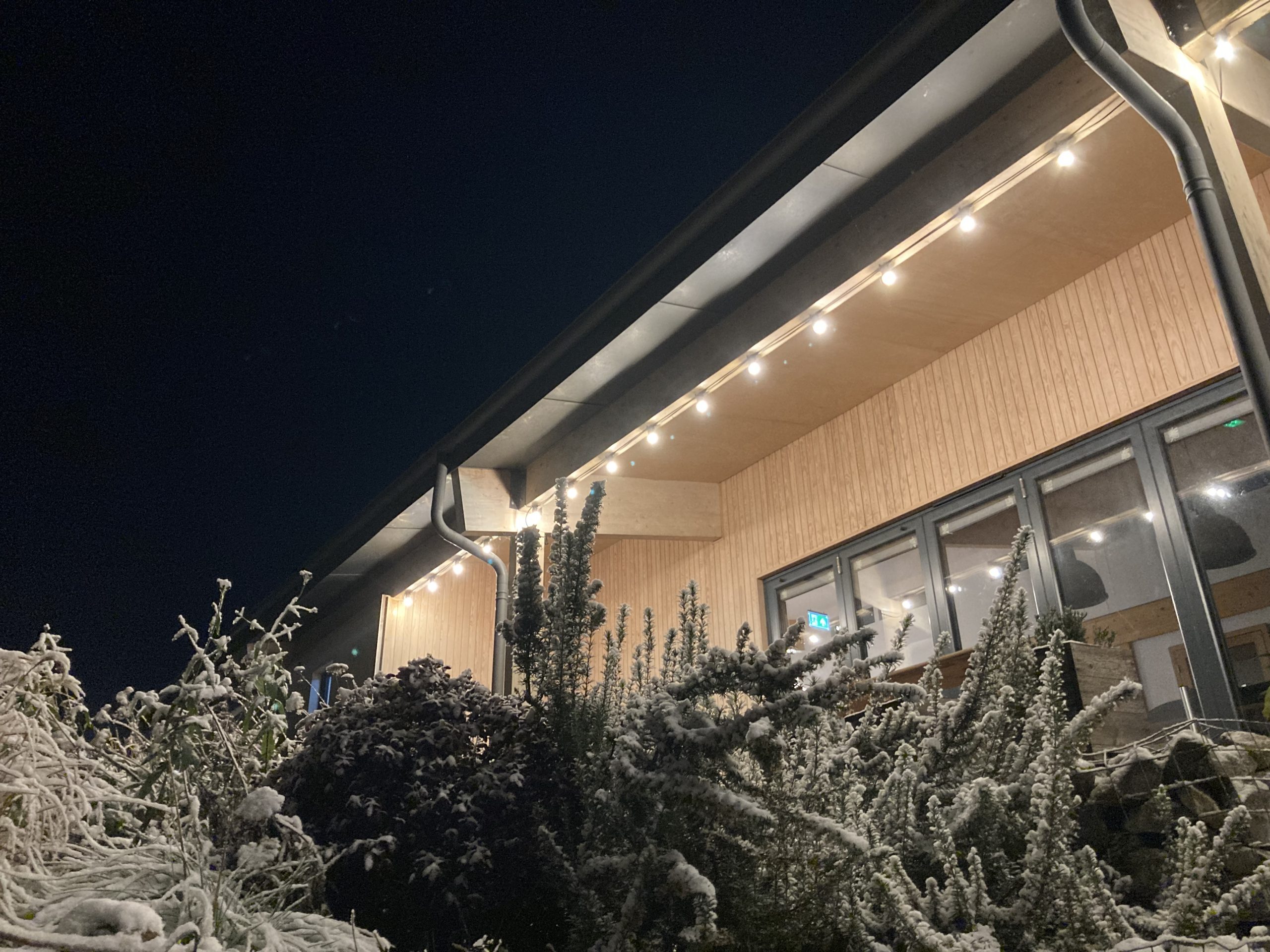 Festoon lights outside Spithurst Hub on a snowy night