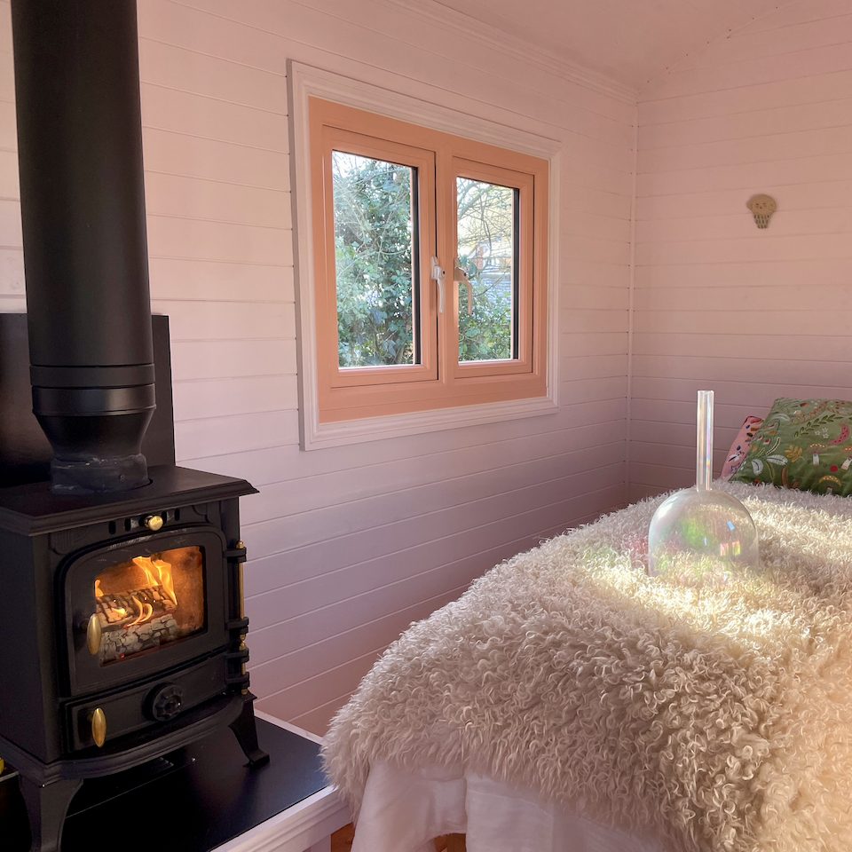 Inside a shepherd's hut at Spithurst Hub with cosy treatment bed and wood fired stove.